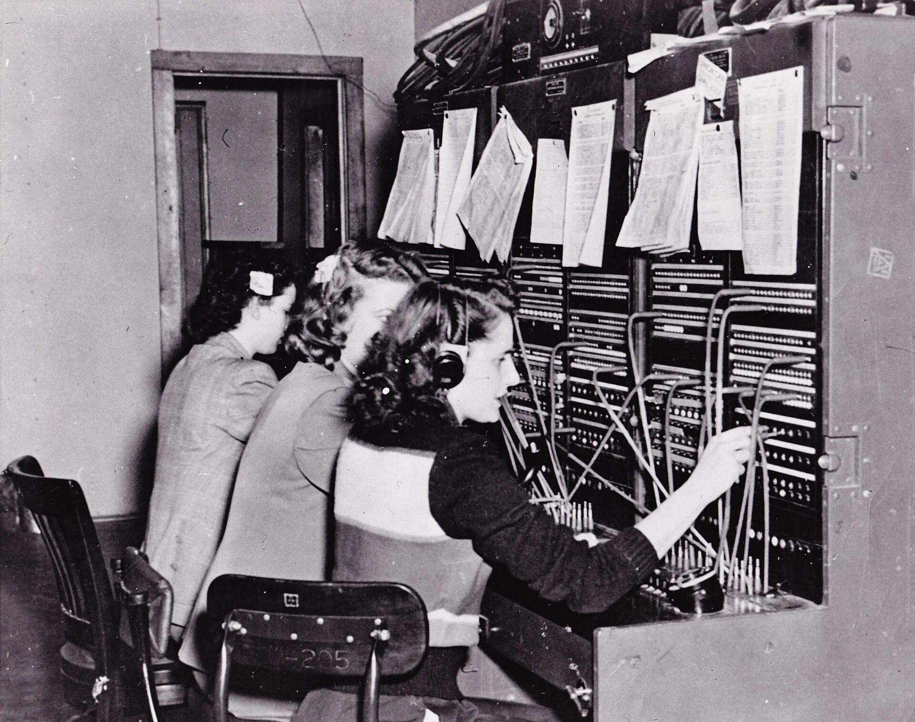 Drie telefonistes bedienen een handmatige telefooncentrale rond 1950